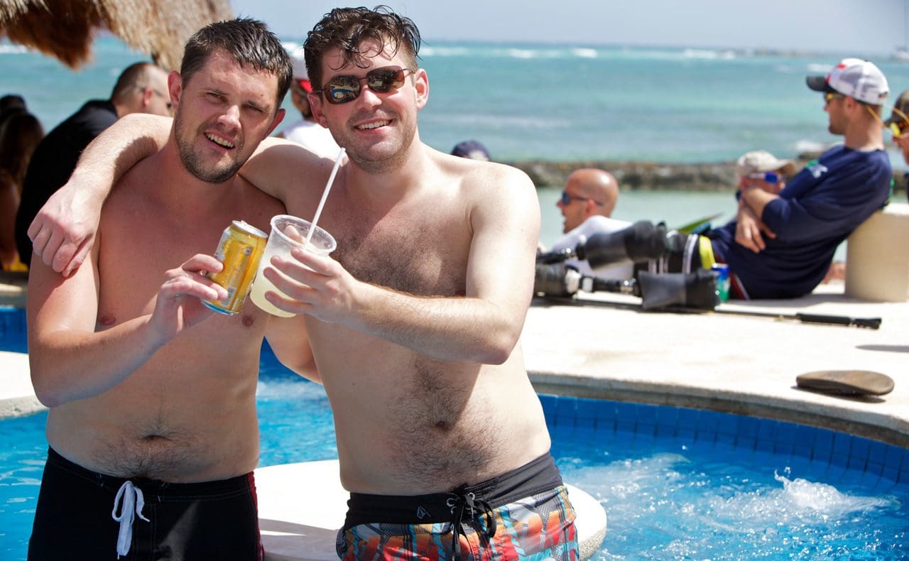 Two men standing next to a pool