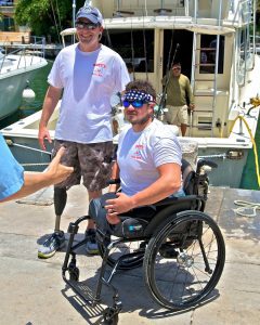 Two men in wheelchairs standing next to a boat.