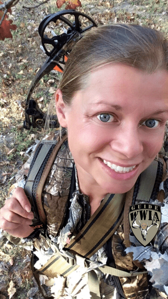 A woman in camouflage holding a bow and arrow.