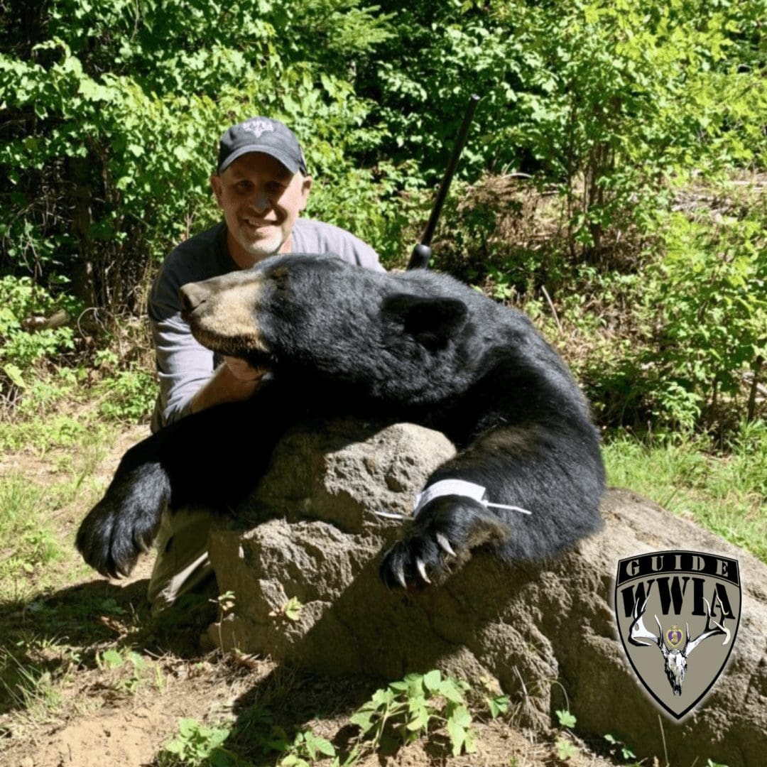Man posing with black bear in forest
