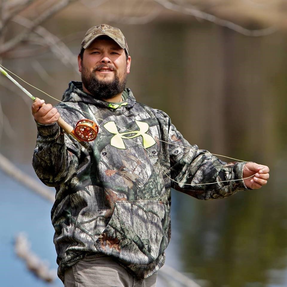 A man in a camouflage hoodie holding a fishing rod