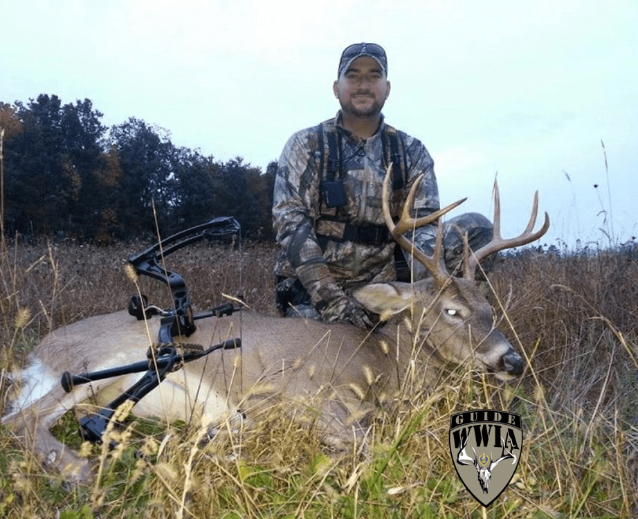 A man posing with a deer in the field.