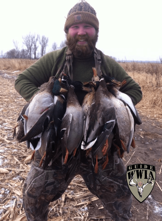 A man holding a bunch of ducks in a field.