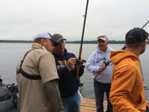 Three men standing on a dock with fishing rods.