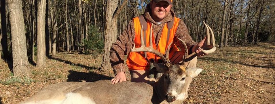 A man posing with a deer that he has just killed