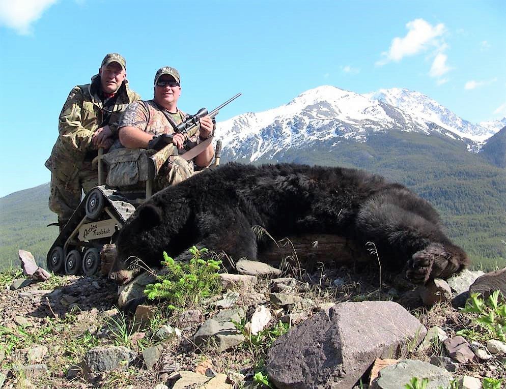 Two men posing with a black bear.