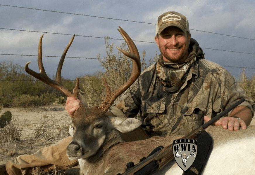 A man posing with a mule deer.