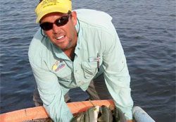 A man holding a net full of fish in the water.