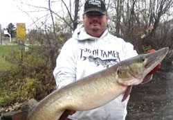 A man holding a large pike on a river.