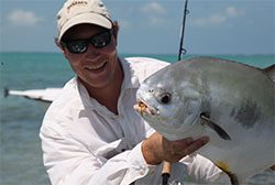 A man holding up a fish on the beach.