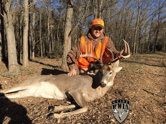 A man posing with a deer he has just killed.