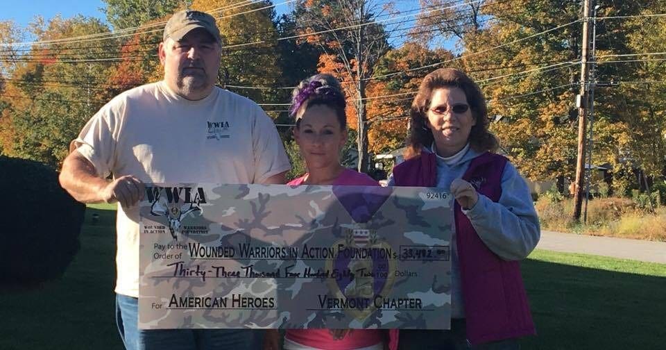 A man and woman holding a check in front of a tree