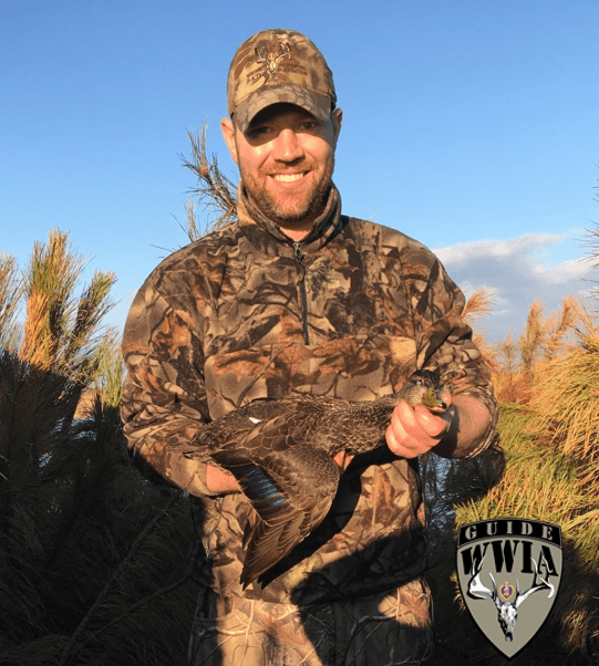 A man in camouflage holding a duck.