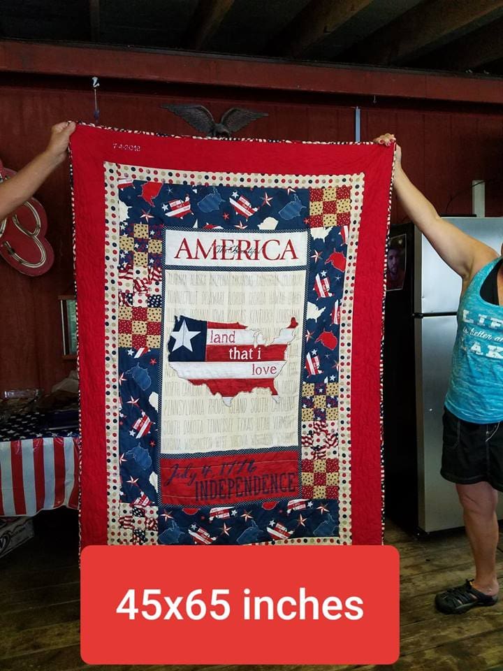 Two women are holding up a quilt that says america