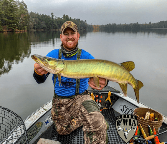 A man holding a large pike in a boat.