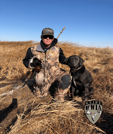 A man posing with two dogs in a field