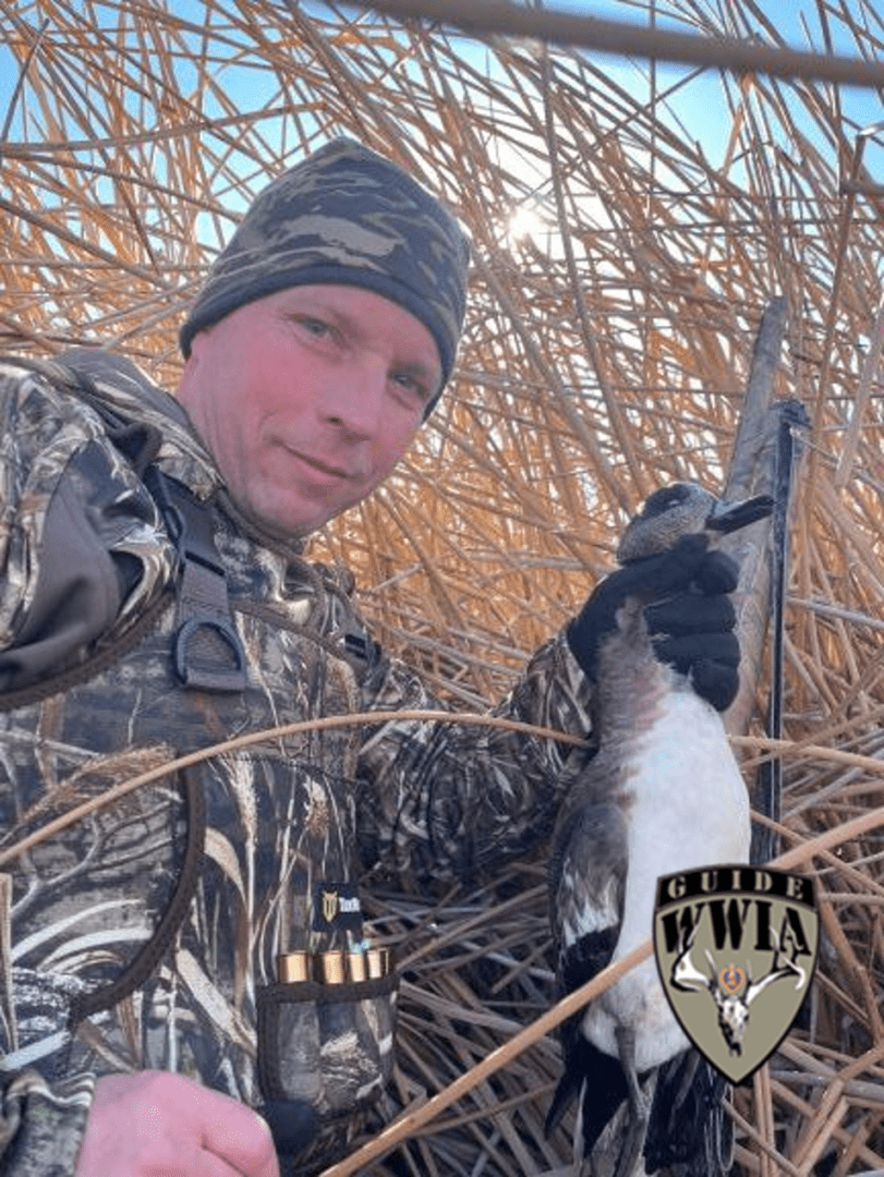 A man in camouflage holding a duck.