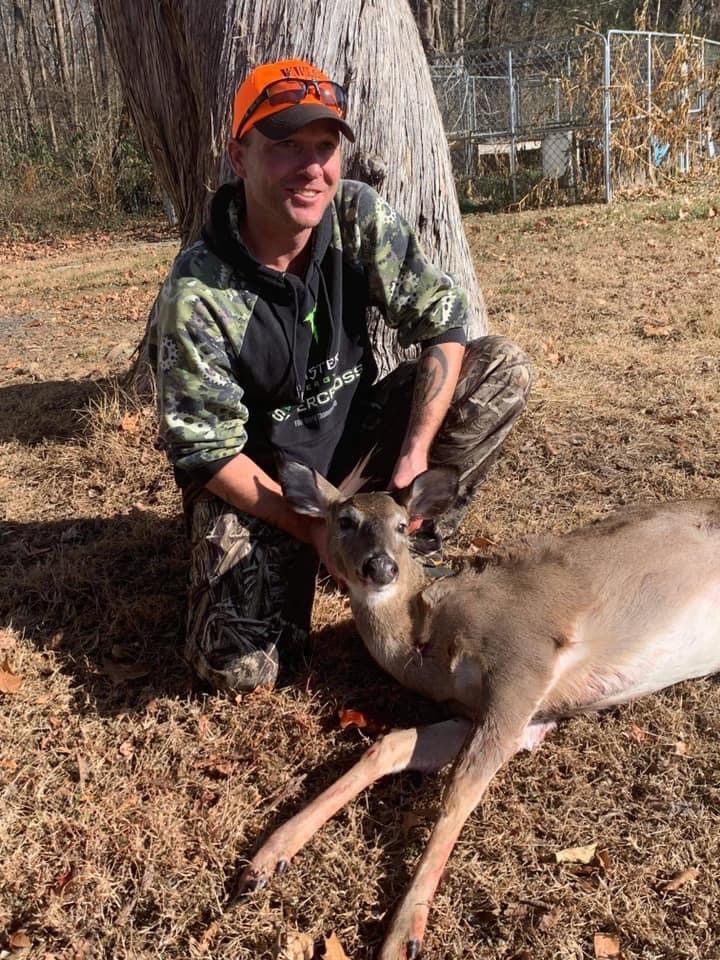 A man kneeling down next to a deer.