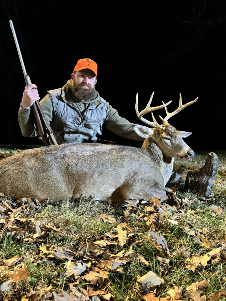 Hunter with large whitetail buck at night