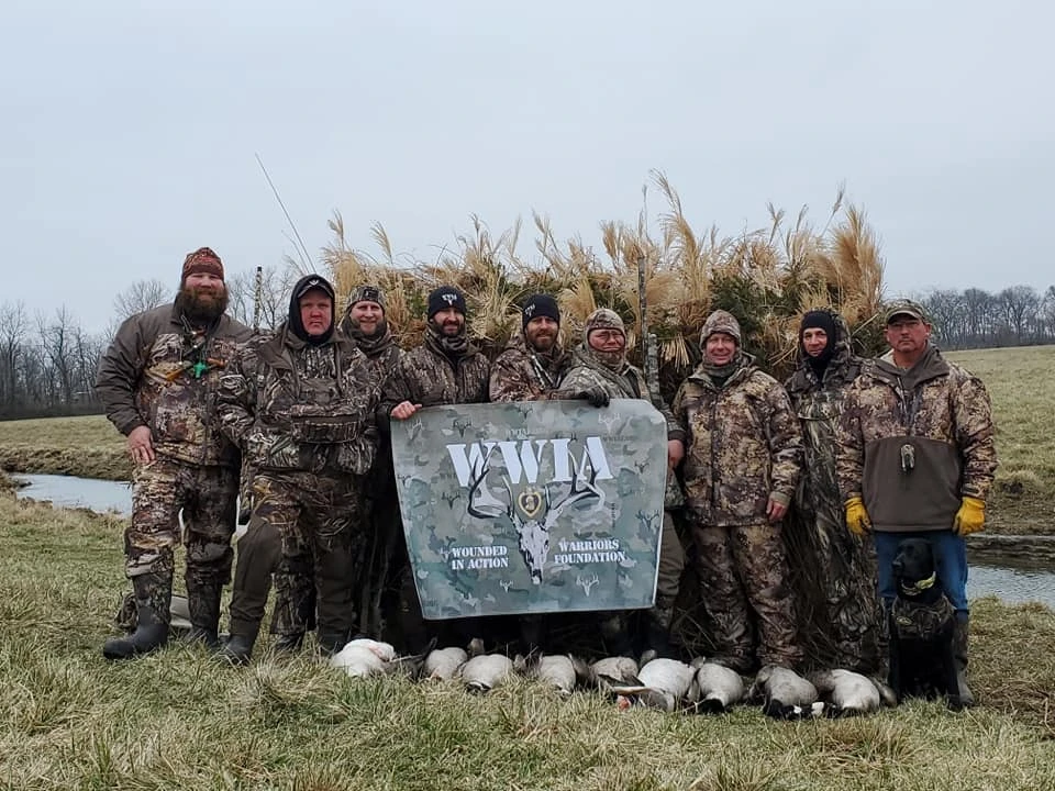 Hunters posing with banner and harvested geese