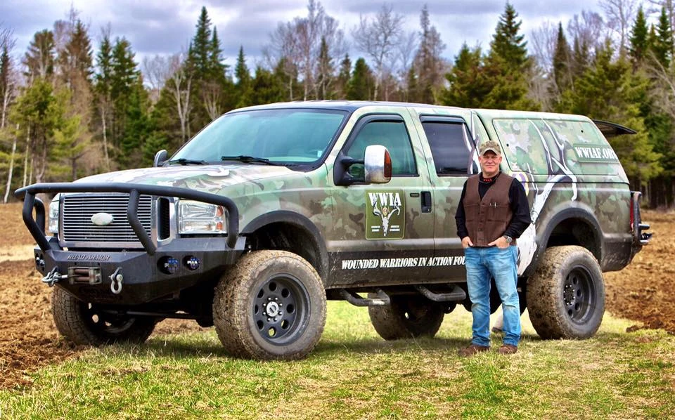 Man standing beside camouflage off road vehicle