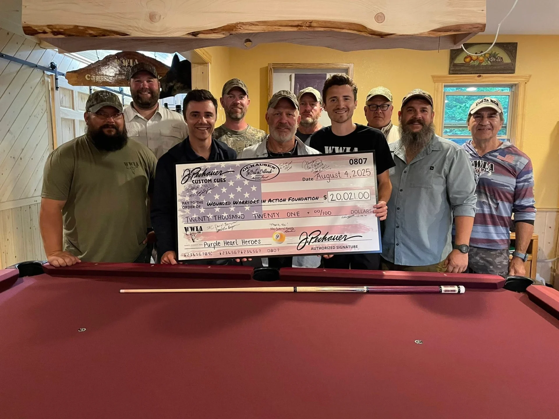 Group holding large check by pool table