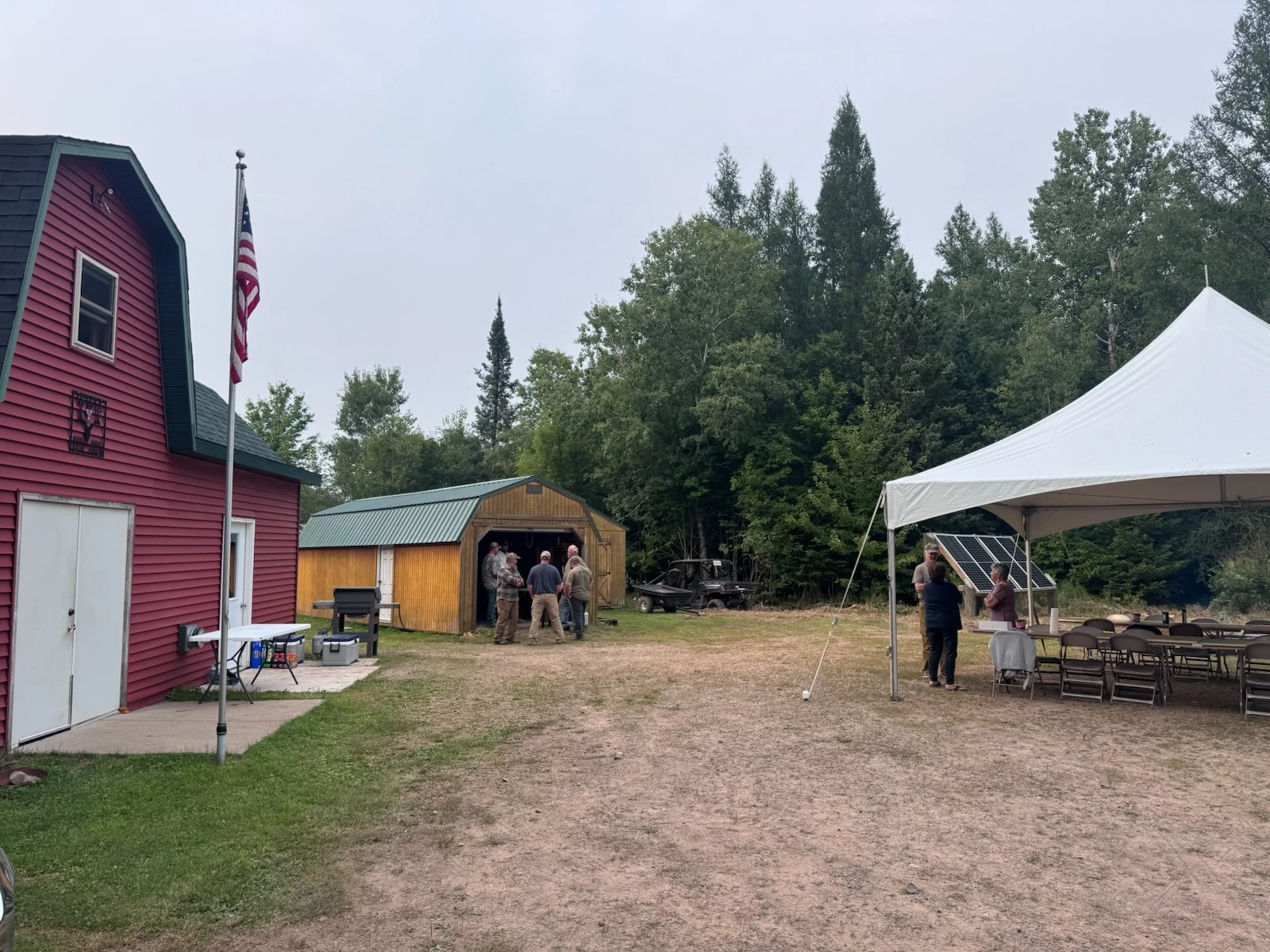 Outdoor gathering with tent and barn
