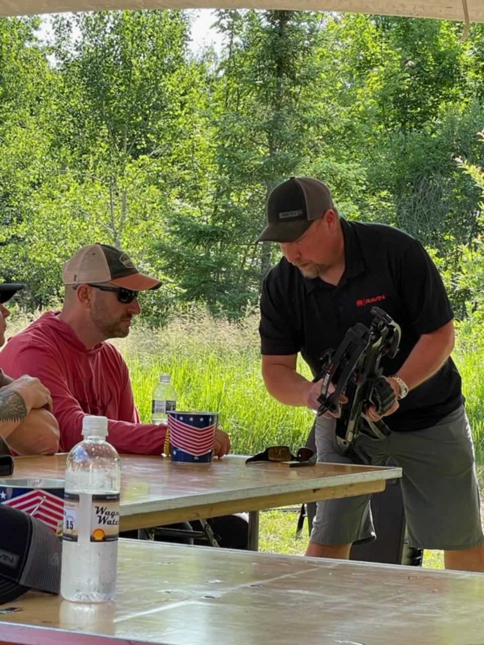Man showing equipment to seated people outdoors