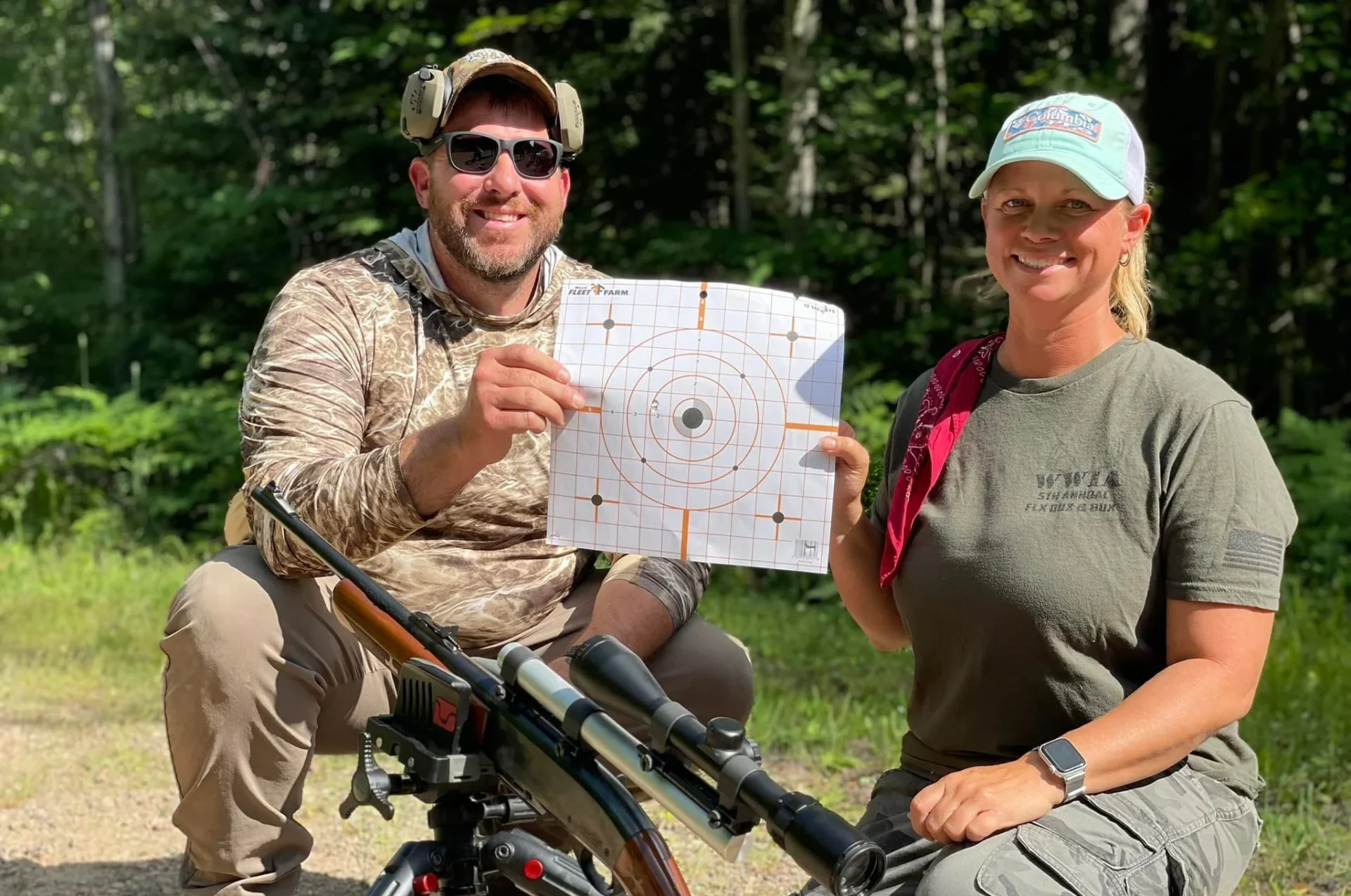 Two people showcasing a shooting target outdoors