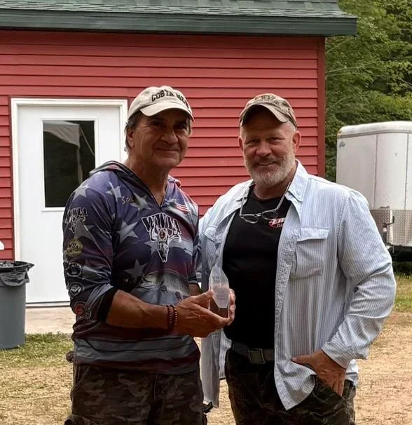 Two men smiling in front of house