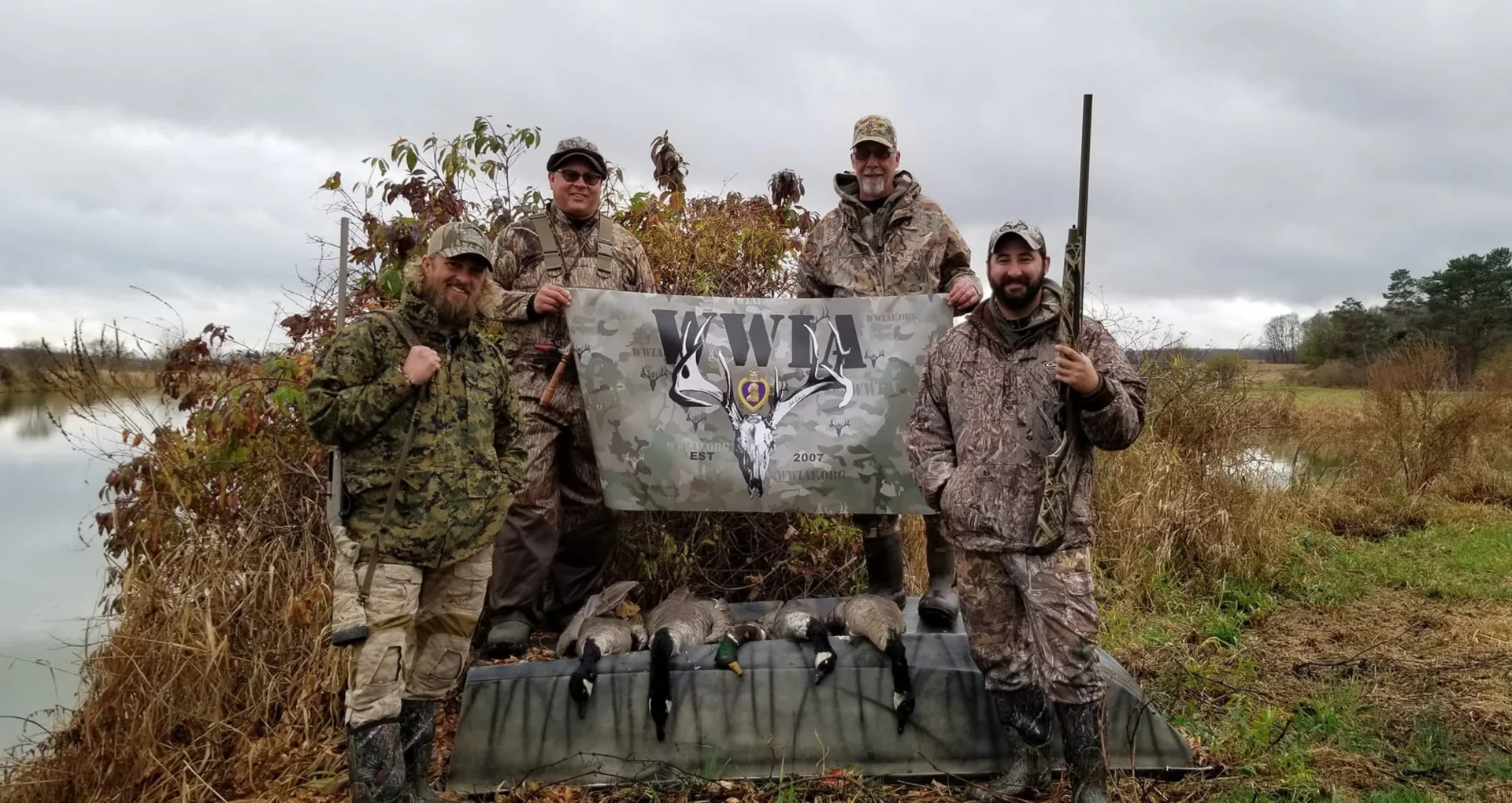 Hunters posing with banner and birds outdoors Wounded Warriors in Action Foundation Hunters posing with banner and birds outdoors