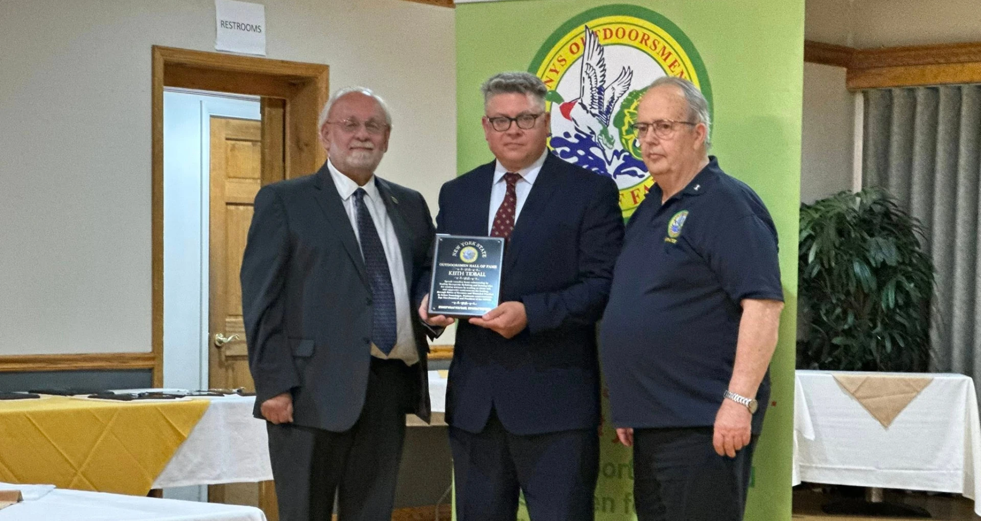 Three men posing with an award plaque