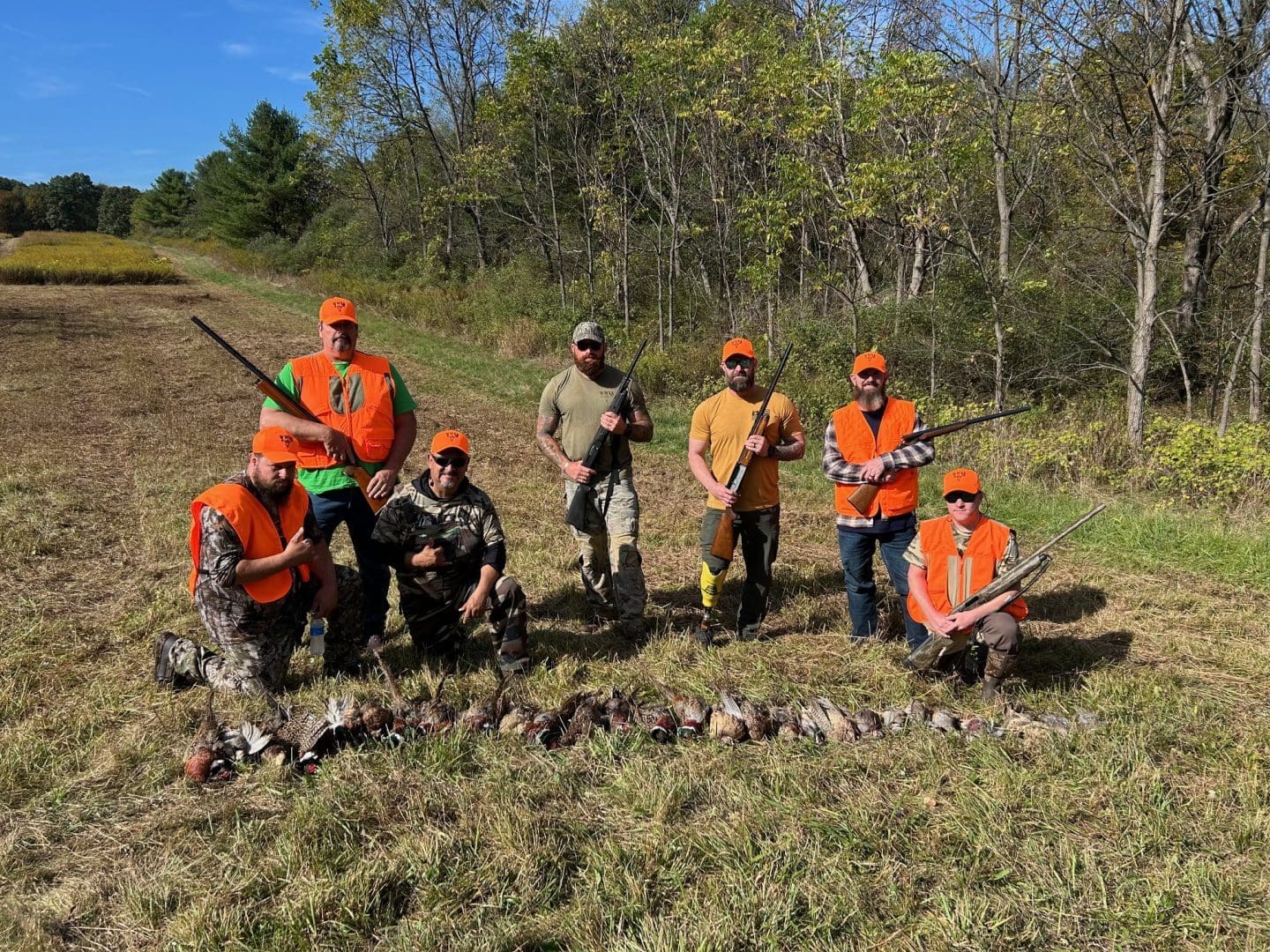 Hunters posing with game in forest clearing