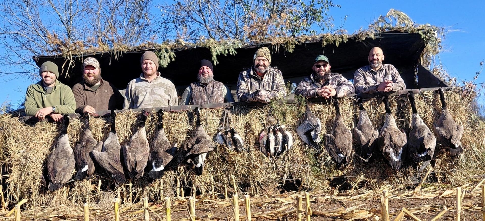 Hunters posing with harvested birds in blind