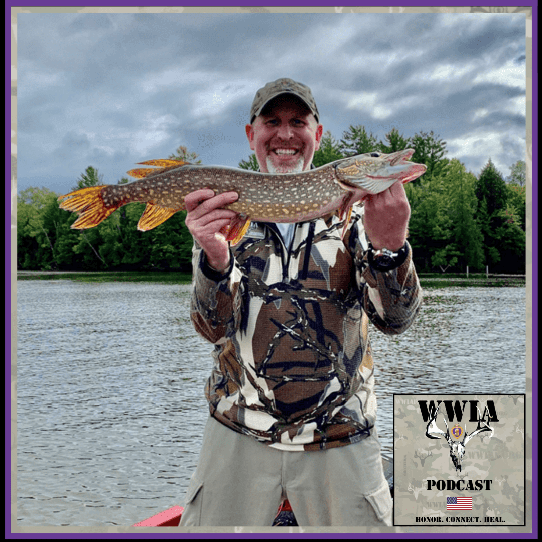 Man holding a large fish by a lake