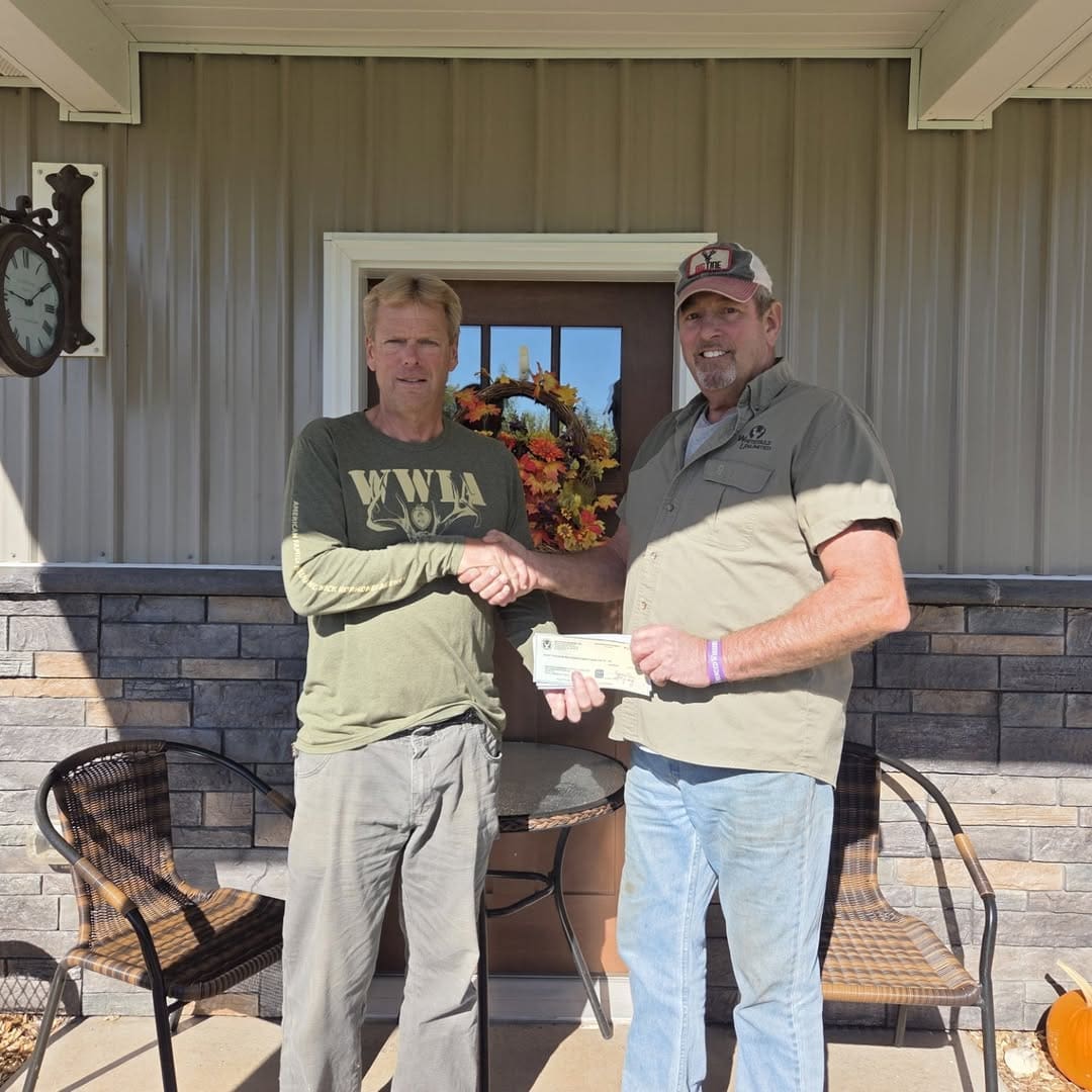 Two men shaking hands holding check